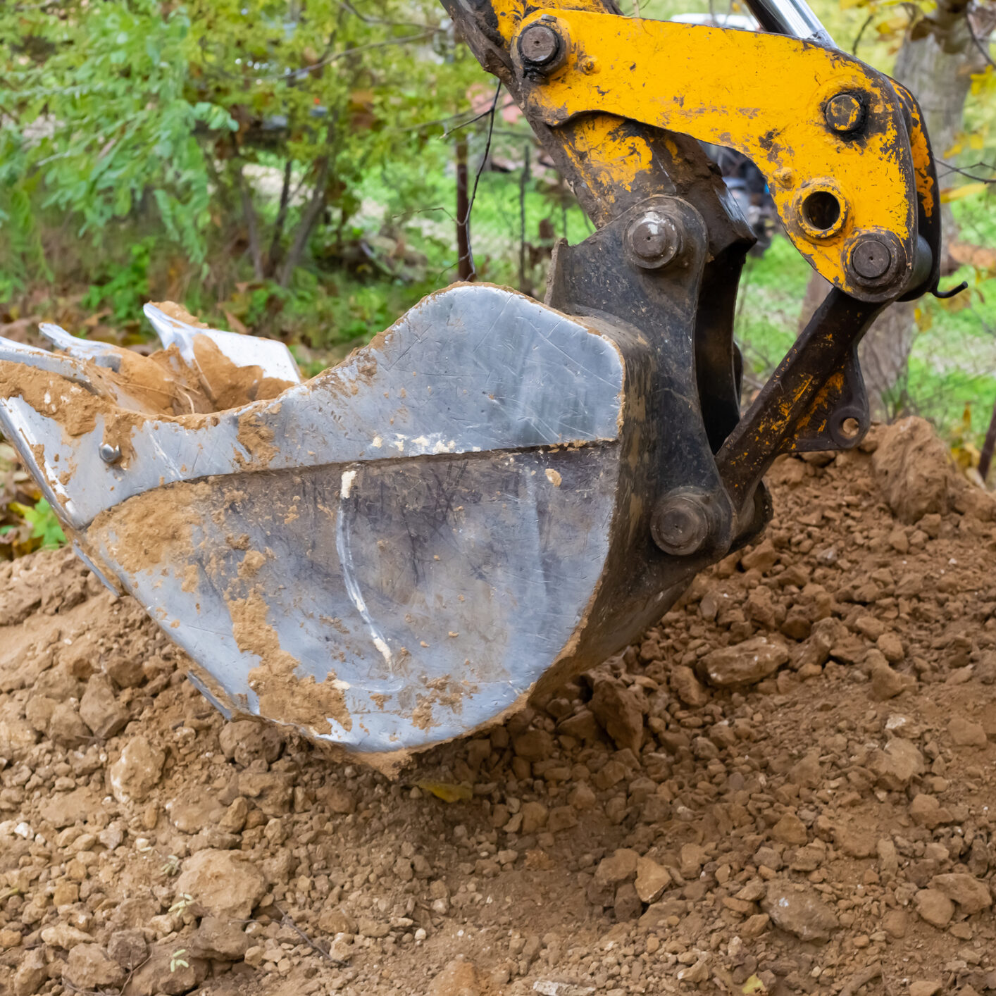 The excavator shovels earth with clay from the pit with a bucket for the construction of a septic tank. Ground work of the machine HYDRAULIC SYSTEM CONTAMINATES & FAILURE TYPES
